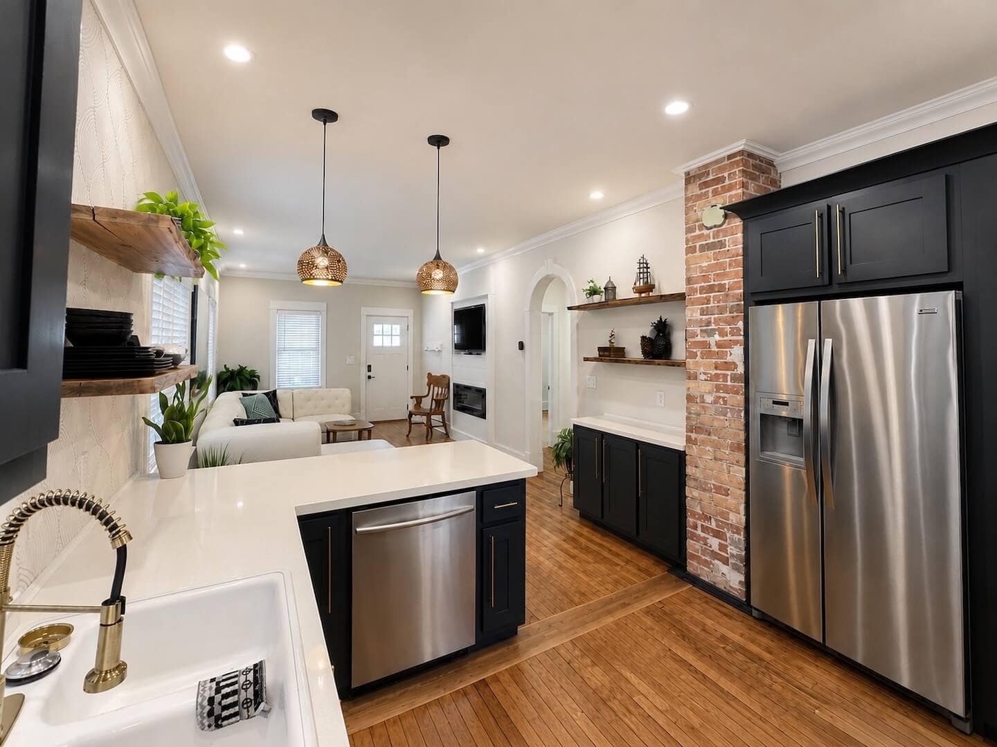 Open kitchen area with black cabinets and white countertops accented with gold hardware