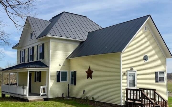 Hail Damaged Metal Roof Replacement Weyauwega Birling Yellow house with black metal roof